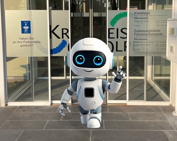 Fotomontage: kleiner wei&szlig;er Roboter schreitet aus der Haupteingangst&uuml;r des Kreishauses, l&auml;chelt und winkt. 
